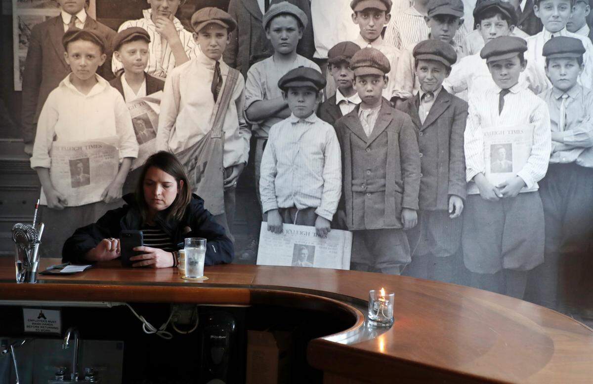 Amanda Brooks of Clayton waits for her to go order at The Raleigh Times in Raleigh, N.C., Tuesday, March 17, 2020. Gov. Roy Cooper ordered bars and restaurants to close at 5 p.m. Tuesday, except for take-out and delivery. The Raleigh Times will offer curbside pickup and delivery via DoorDash.