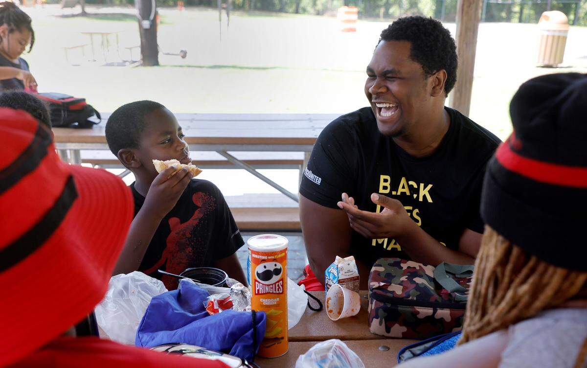 N.C. State offensive lineman Tim McKay laughs with Raleigh Parks and Recreation camper Redmond Graves, 8, while hanging out with him Wednesday, June 22, 2022. As part of the Wolfpack’s ‘D Leary Delivers’ campaign, N.C. State quarterback Devin Leary along with offensive linemen McKay, Bryson Speas and Derrick Eason brought a SnoCone truck to two Raleigh camps, hung out with the campers and then made snow cones for them.