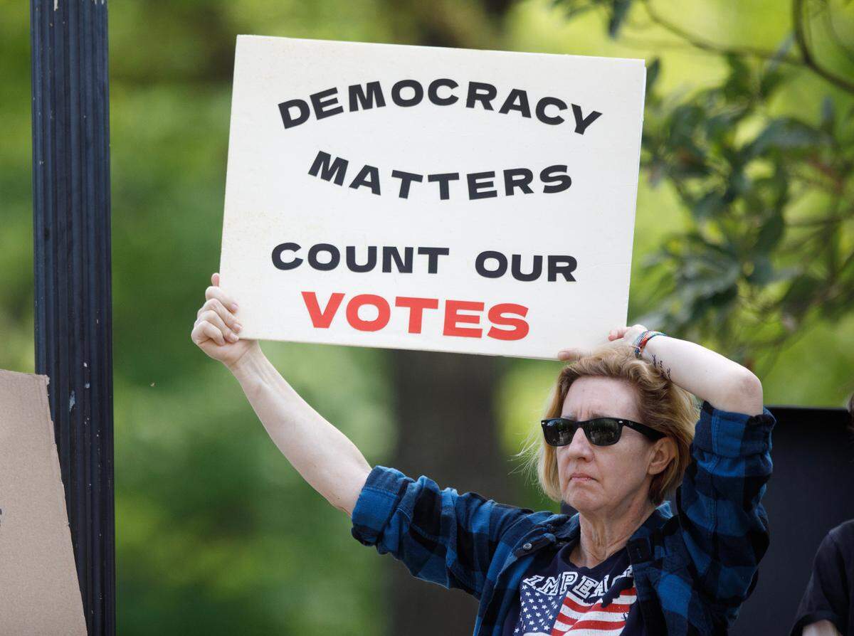 Patryce Britton holds a sign during a rally on Monday, April 14, 2025, in Raleigh, N.C., held in protest of Republican state Supreme Court candidate Jefferson Griffin’s challenge of 65,000 votes in the November election.