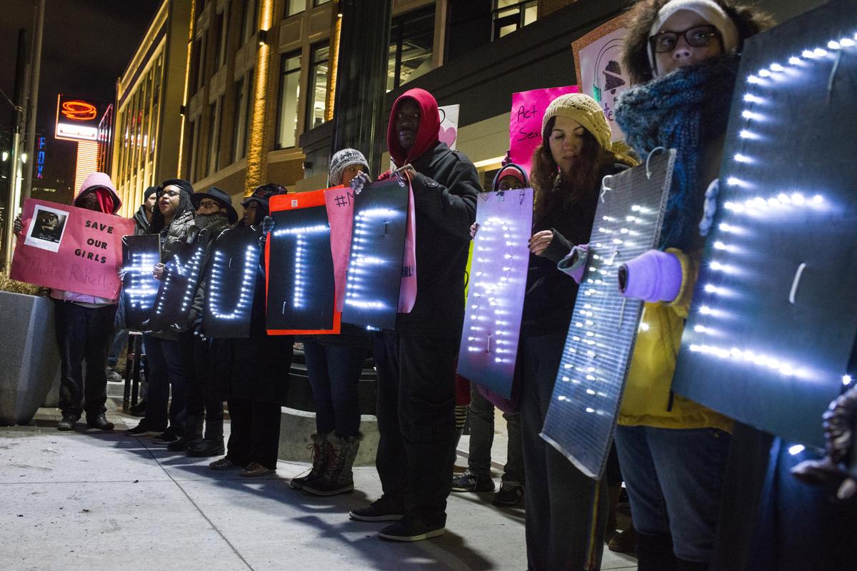 Protesters hold signs that say "Mute R. Kelly" outside his concert in Detroit in February. North Carolina activists are scheduled to protest May 11 and 12 at concerts in Greensboro and Raleigh, NC.