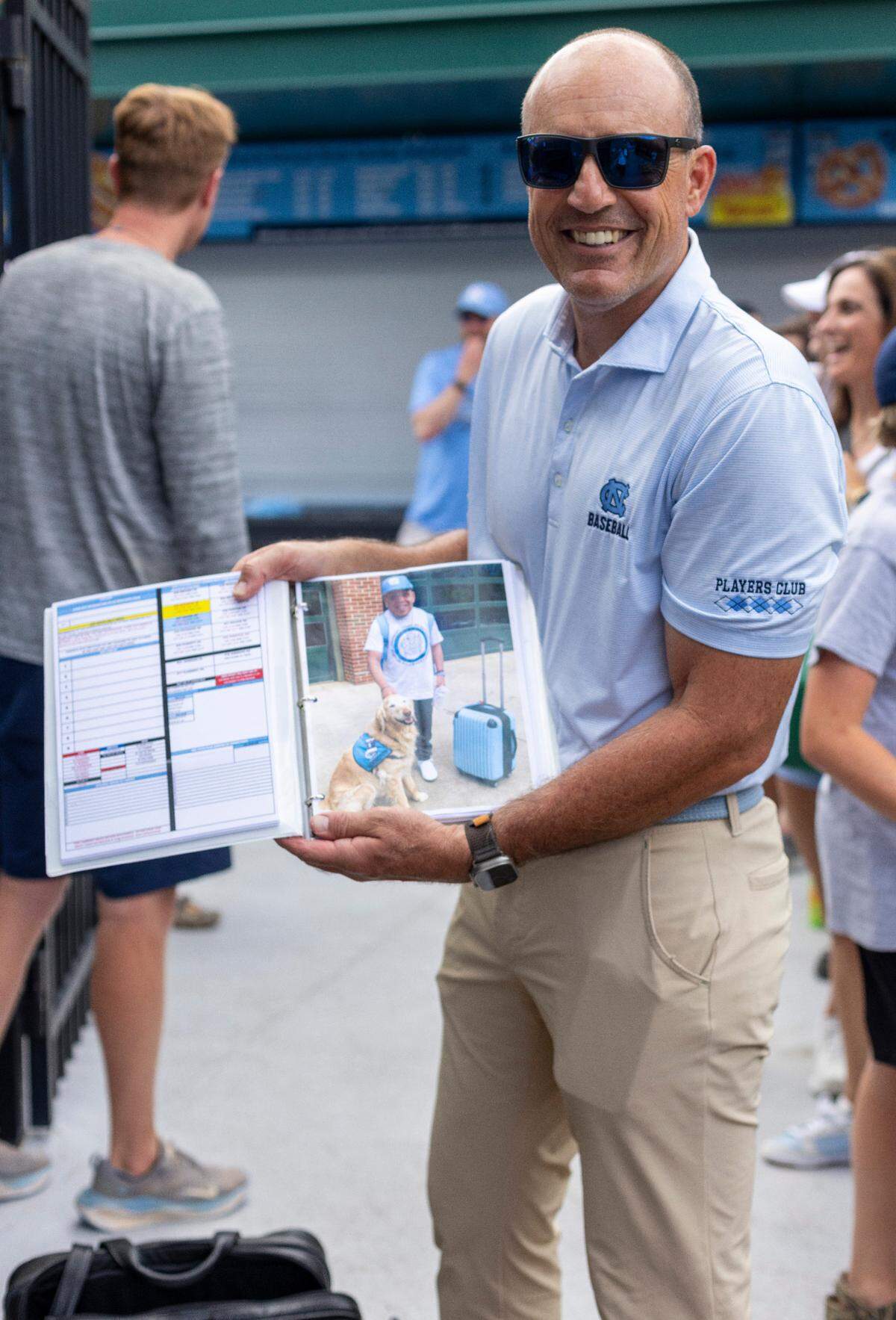 North Carolina coach Scott Forbes displays a photo of J.R. Anton in one of his game notebooks he has packed for the trip to the College Word Series on Tuesday, June 11, 2024 at Boshamer Stadium in Chapel Hill, N.C. J.R. Anton became a friend of the Tar Heel baseball program in 2006 during the College World Series in Omaha. Upon his death last month, the players have all written J.R.’s initials on their game caps as a tribute to him.