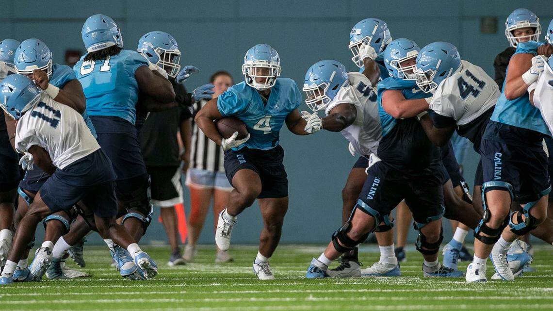 North Carolina running back Caleb Hood (4) breaks through the line during the Tar Heels’ first day of practice on Thursday, August 5, 2021 in Chapel Hill N.C.