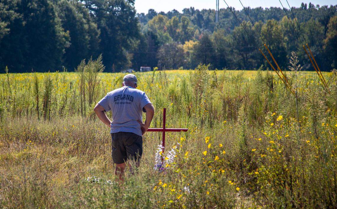 Stan Dean, the grandfather of Lyric Woods, stands over a makeshift memorial that sits a few yards from the entrance of a gravel road in Orange County Tuesday, Sept. 20, 2022. The Orange County Sheriff’s Office said Monday the two young people found shot and killed Sunday in western Orange County are missing teens Lyric Woods, 14, and Devin Clark, 18.