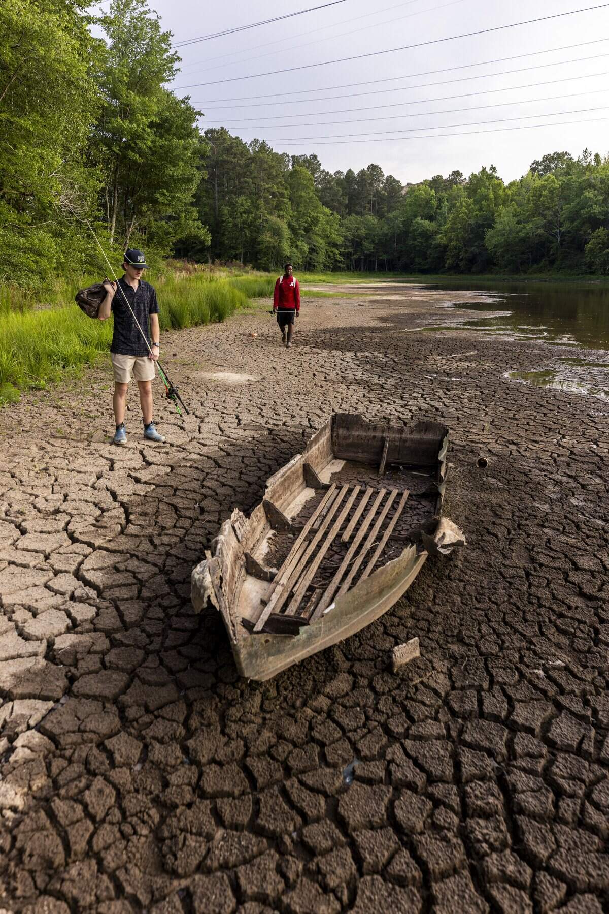 Connor Fox of Durham, left, and Jayden Williams of Raleigh, both 21, discover the wreck of a small fishing boat on a partially exposed lake bed while fishing along the shoreline of Newcombs Lake on Friday, June 26, 2026. Raleigh is 18.59 inches below its average rainfall since August 2025, and Falls Lake, Raleigh's primary water source, is 5 feet below its target level. As of mid-June, Durham was about 10 to 12 inches below normal rainfall since the start of the year.