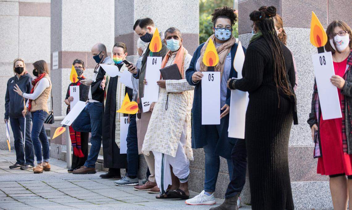 Clergy and members of community organizations await the start of a prayer vigil while holding candle posters that represent each year of the 28-year Leandro case. The vigil, hosted by Pastors for NC Children in Raleigh, N.C., urges the N.C. General Assembly to fund the Leandro Plan as a court hearing is held about the case on Monday, Oct. 18, 2021.