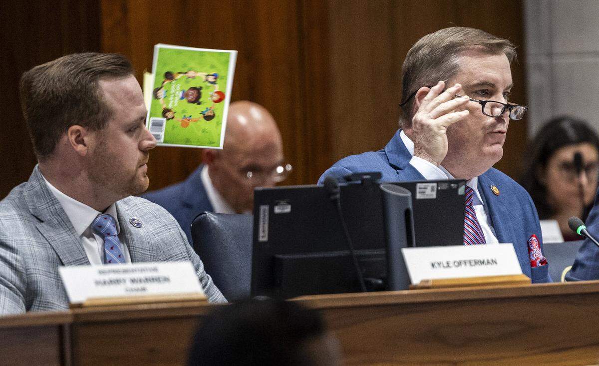 N.C. House Majority Leader Brenden Jones tosses a book he finds offensive over his shoulder while questioning Chapel Hill-Carrboro City Schools Superintendent Rodney Trice and School Board Chair George Griffin during a sometimes tense House committee hearing on Wednesday, Dec. 10, 2025, in the Legislative Building auditorium in Raleigh. During the hearing, Jones cited and tossed several children’s books from a third-party list that had previously appeared on the district’s website.