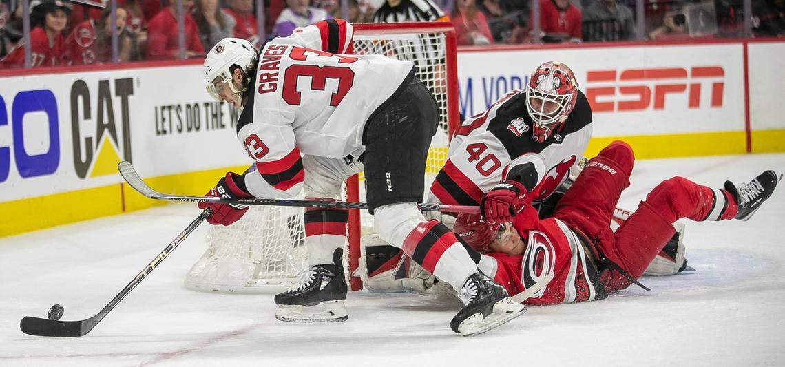 The New Jersey Devils Ryan Graves (33) clears the puck after a scoring attempt by the Carolina Hurricanes Jesse Piljujarvi (13) on goalie Akira Schmid (40) in the first period during Game 1 of their second round Stanley Cup playoff series on Wednesday, May 3, 2023 at PNC Arena in Raleigh, N.C. 