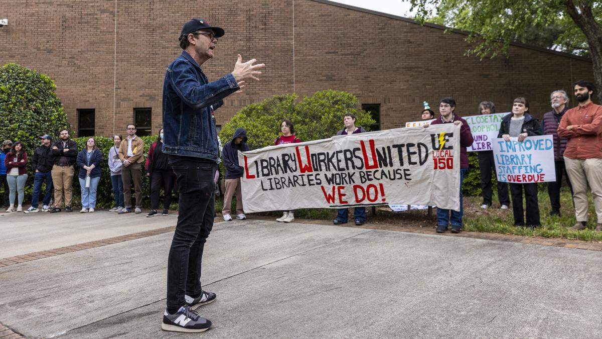 Dante Strobino, a union organizer, speaks as Wake County library workers and supporters demonstrate outside the Wake County Commons Building in Raleigh before a public hearing on the county’s proposed fiscal 2027 budget on Monday, May 11, 2026. Protesters say chronic understaffing and reductions in staff hours are affecting library programming and services.
