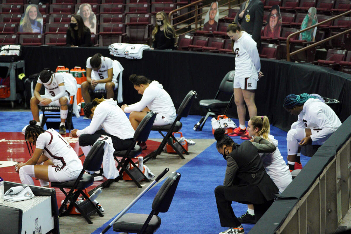 South Carolina coach Dawn Staley, right front, joins Olivia Thompson and most of the team in kneeling during the national anthem before an NCAA college basketball game against North Carolina State on Thursday, Dec. 3, 2020, in Columbia, S.C. Elysa Wesolek was the lone player on the team who stood for the anthem.