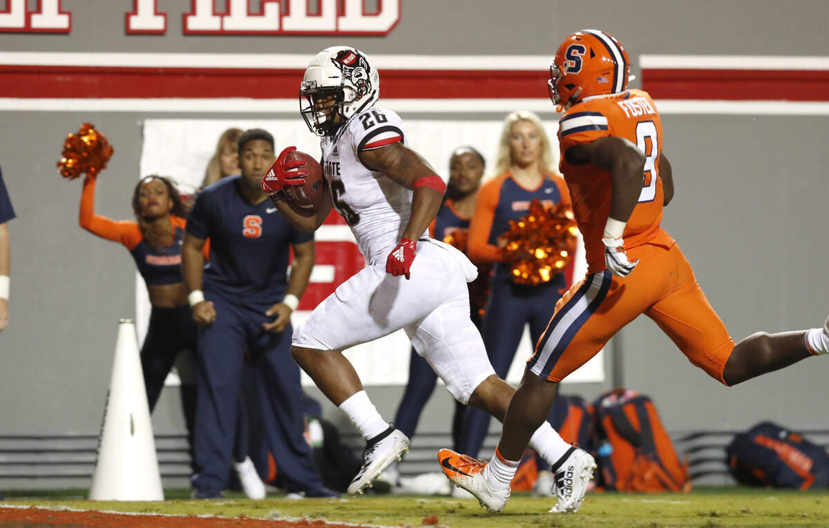 N.C. State’s Trent Pennix (26) pulls in a 32-yard touchdown reception as Syracuse defensive back Christopher Fredrick (3) chases him during the first half of N.C. State’s game against Syracuse at Carter-Finley Stadium in Raleigh, N.C., Thursday, Oct. 10, 2019.