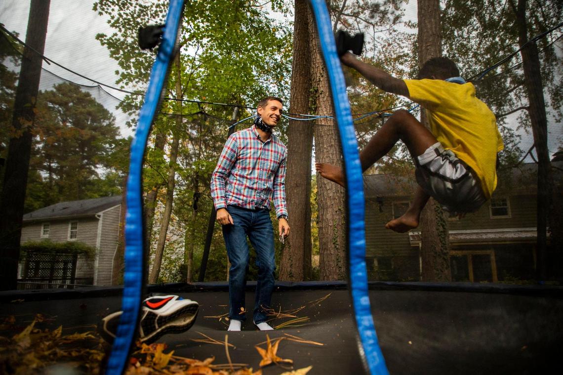 Dave Pearson jumps on the trampoline with his foster son, on Tuesday, Oct. 27, 2020, in Durham, N.C.