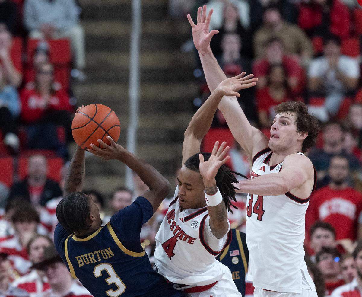 N.C. State’s Breon Pass and Ben Middlebrooks contest a shot by Notre Dame’s Markus Burton during the second half of the Wolfpack’s 66-65 win on Wednesday, Jan. 8, 2025, at Lenovo Center in Raleigh, N.C.