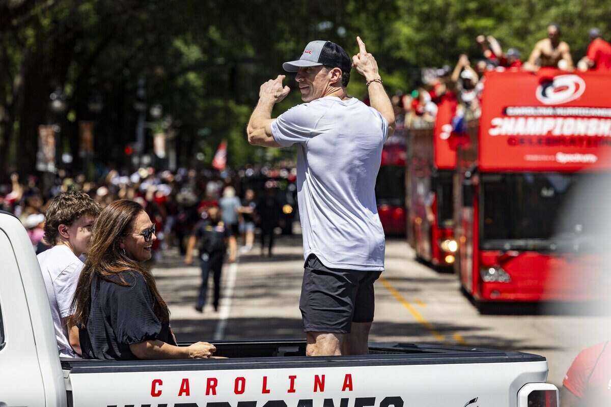 Carolina Hurricanes coach Rod Brind'Amour acknowledges the crowd and points toward buses carrying players as thousands of Carolina Hurricanes fans gather in downtown Raleigh on Saturday, June 20, 2026, during a parade and rally celebrating the Hurricanes' Stanley Cup Final victory over the Vegas Golden Knights. The Hurricanes won the series 4-2 to capture the Stanley Cup for the second time in franchise history.