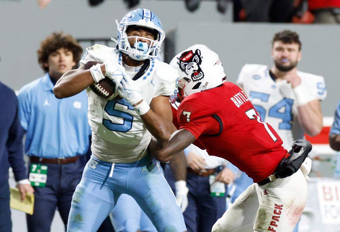 N.C. State cornerback Shyheim Battle (7) hits North Carolina wide receiver J.J. Jones (5) during the second half of N.C. State’s 39-20 victory over UNC at Carter-Finley Stadium in Raleigh, N.C., Saturday, Nov. 25, 2023.