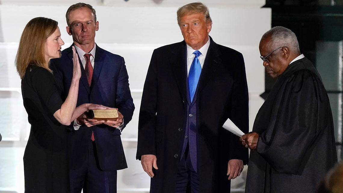 President Donald Trump watches as Supreme Court Justice Clarence Thomas administers the Constitutional Oath to Amy Coney Barrett on the South Lawn of the White House White House in Washington, Monday, Oct. 26, 2020, after Barrett was confirmed to be a Supreme Court justice by the Senate earlier in the evening. Holding the Bible is Barrett’s husband, Jesse Barrett. (AP Photo/Alex Brandon)