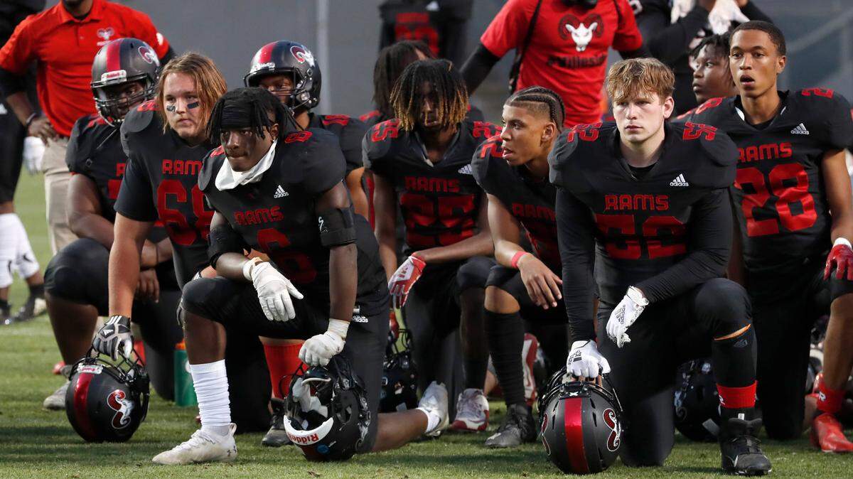 Members of the Rolesville football team watch as Vance accepts its trophy after Vance High School’s 35-14 victory over Rolesville High School in the NCHSAA 4AA state championship at Carter-Finley Stadium in Raleigh, N.C., Saturday, May 8, 2021. Wake County is dropping the requirement that student-athletes wear face coverings outdoors when they’re on the sidelines.