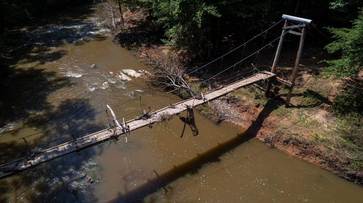 An aerial view of a flood-damaged pedestrian suspension bridge on Monday, July 21, 2025, as Eno River State Park remains closed due to flooding from Tropical Depression Chantal.