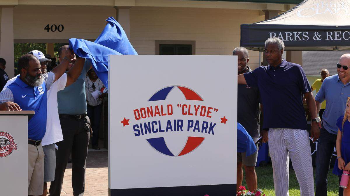 Donald ‘Clyde’ Sinclair, right, and Danny Banks, left, unveil a new sign Saturday at the park in Clayton now named in Sinclair’s honor.