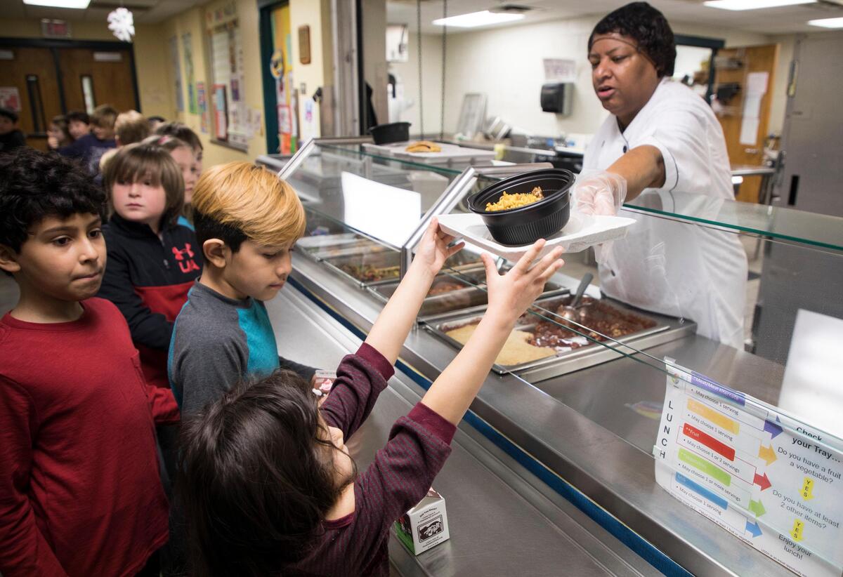 Brenda Terry hands out Cuban pork and rice bowls to students at George Watts Elementary School in Durham on Jan. 24, 2019. State lawmakers plan to reinvest some of the money public schools didn’t get due to the private school voucher program into bonuses for cafeteria workers.
