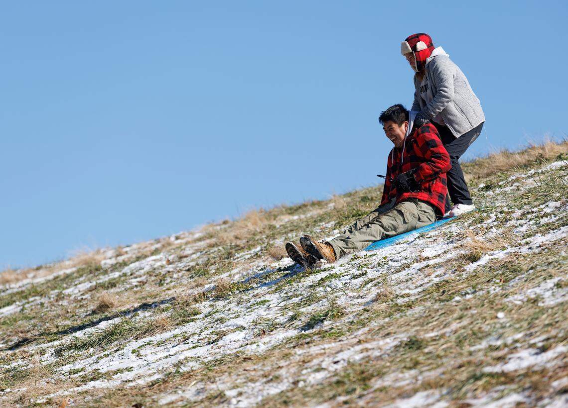 Wilmer Morales and Blanca Escobar sled down a hill at Bond Park on Wednesday, Jan. 22, 2025, in Cary, N.C.