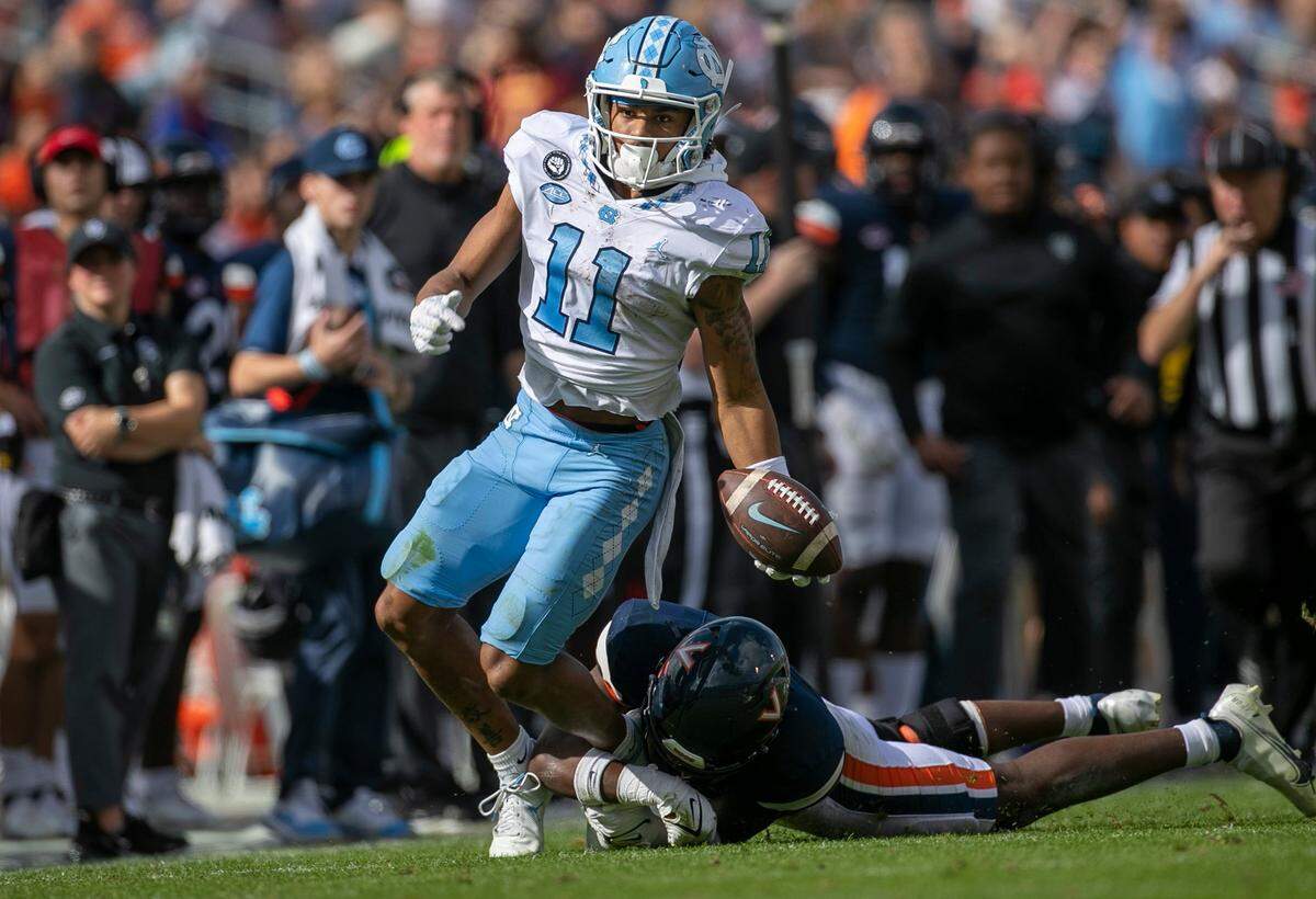North Carolina’s Josh Downs (11) looks for running room against Virginia’s Coen King (9) after a 32-yard pass reception from quarterback Drake Maye in the third quarter on Saturday, November 5, 2022 at Scott Stadium in Charlottesville, Va. Downs had 15 pass receptions for 166 yards in the Tar Heels’ victory.