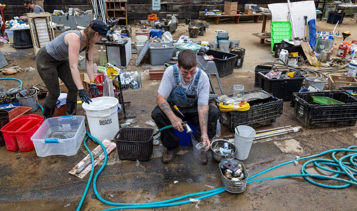 Volunteers Kristin Giles and Raymond Dauteuil clean the inventory from the historic Gentry Hardware on Friday, October 4, 2024 in Hot Springs, N.C. Flood waters from Hurricane Helene flooded adjacent Spring Creek in the center of town, wiping out most of the businesses.