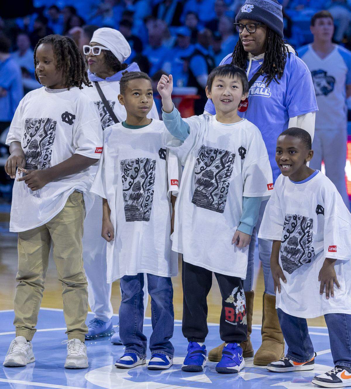 Jinghe Liu raises his hand as he is acknowledged as the winner of the Black History Month t-shirt design, during the North Carolina vs Louisville basketball game, on February 23, 2026 at the Smith Center in Chapel Hill, N.C. 