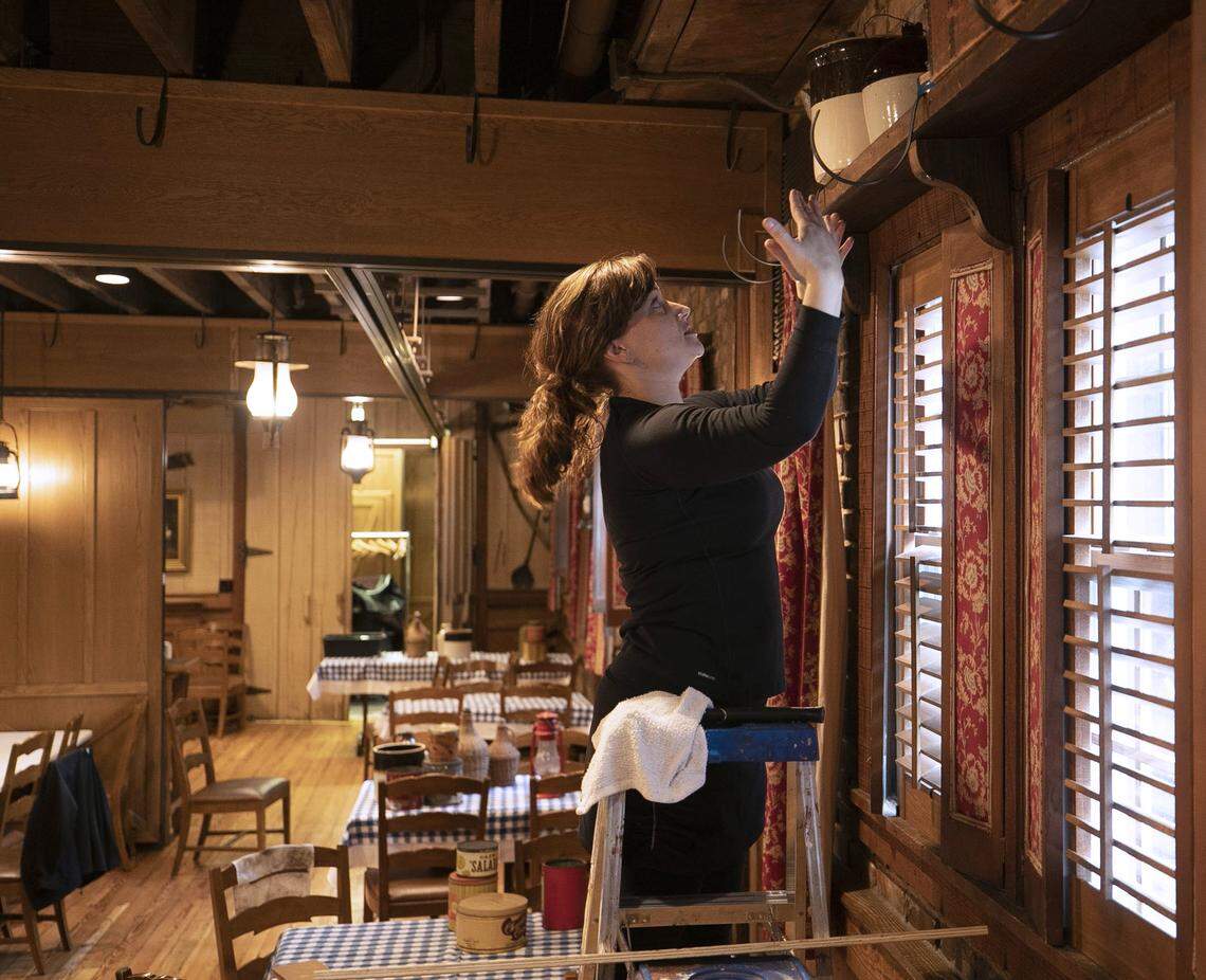 Angus Barn employee Rebecca Layton arranges an antique display in one of the dining rooms on Tuesday, May 19, 2020 in Raleigh, N.C. Owner Van Eure is preparing to open her dining rooms in anticipation of Gov. Roy Cooper lifting his coronavirus restrictions.