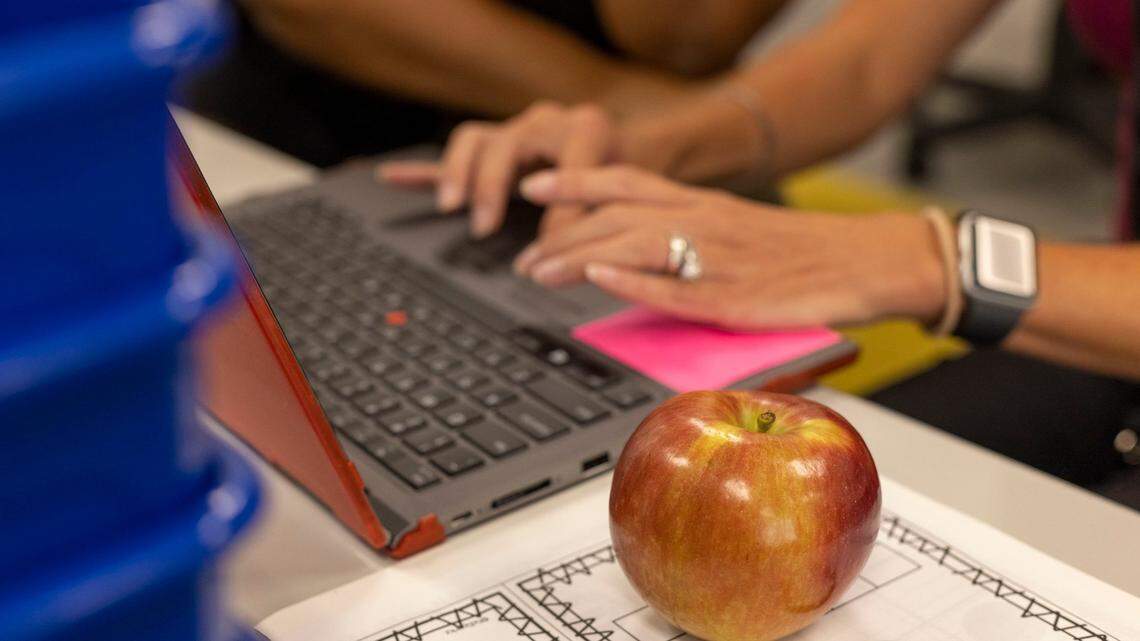 Barton Pond Elementary School first grade teacher Cindy Fields looks over her student list on the laptop with an apple close by on Wednesday morning, August 17, 2022 in Raleigh, N.C. Fields said she brought the apple for her breakfast on the first teacher work day at Barton Pond Elementary School.