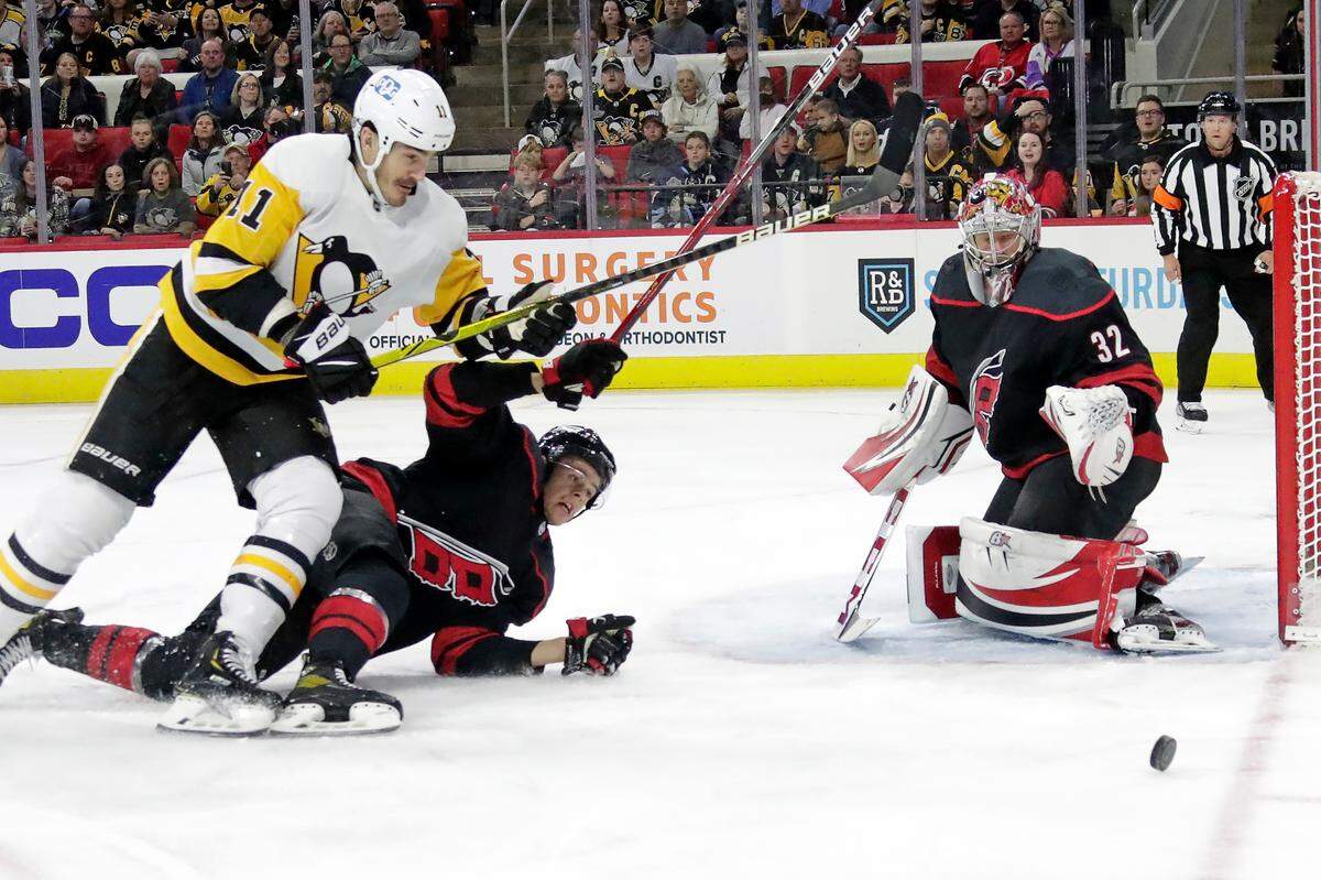 Pittsburgh Penguins center Brian Boyle (11) and Carolina Hurricanes center Jesperi Kotkaniemi, center, and goaltender Antti Raanta (32) watch a loose puck during the first period an NHL hockey game Friday, March 4, 2022, in Raleigh, N.C. (AP Photo/Chris Seward)