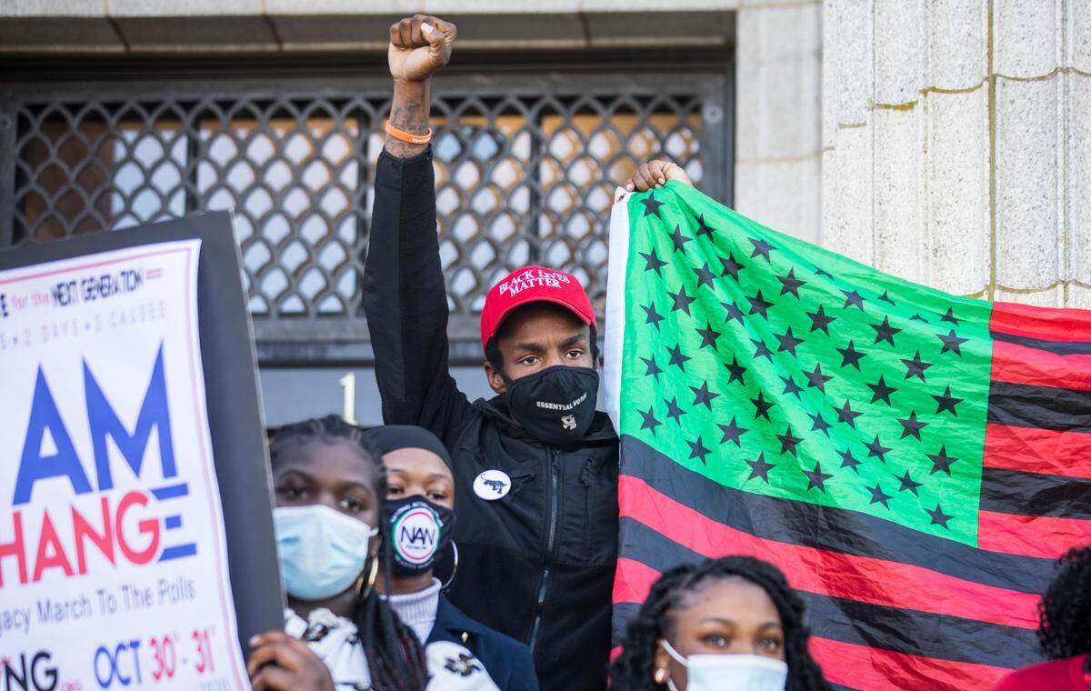 Avery Harvey holds his fist up while standing on the steps of the Alamance County Historic Courthouse during a press conference on Oct. 14, 2020, announcing a march to the polls.