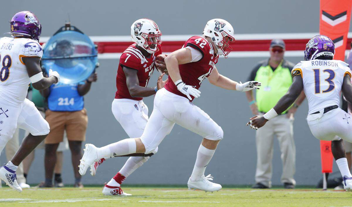 N.C. State’s Dylan Autenrieth (42) provides blocking for quarterback Matt McKay (7) as he runs for 21-yard touchdown run past East Carolina’s Davondre Robinson (13) during the second half of N.C. State’s 34-6 victory over East Carolina University at Carter-Finley Stadium in Raleigh, N.C., Saturday, August 31, 2019.