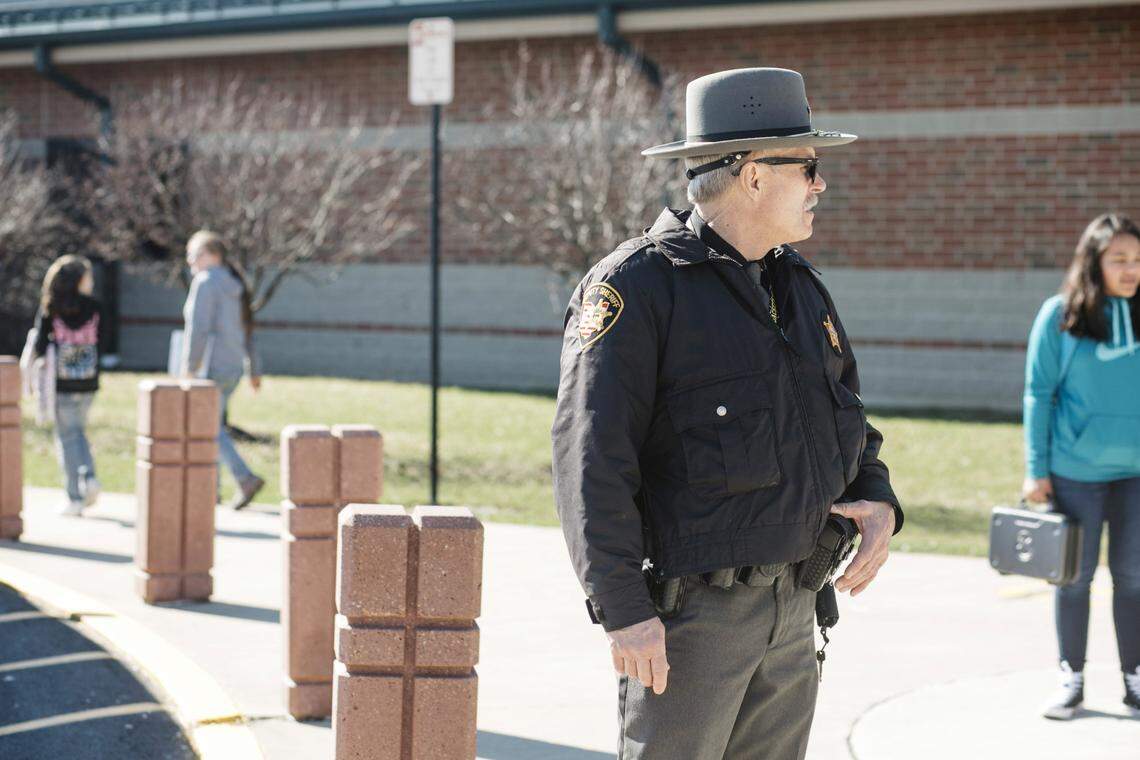 Rick Cron, a school resource officer with the Shelby County (Ohio) Sheriff’s Office, watches students and the parking lot during dismissal earlier this year. Leaders in Henderson County, NC, decided this spring to hire armed guards to work at all 23 public schools in the western North Carolina community. NC schools are also allowed to have unpaid, volunteer armed guards on campus because of a law the state passed in 2013.