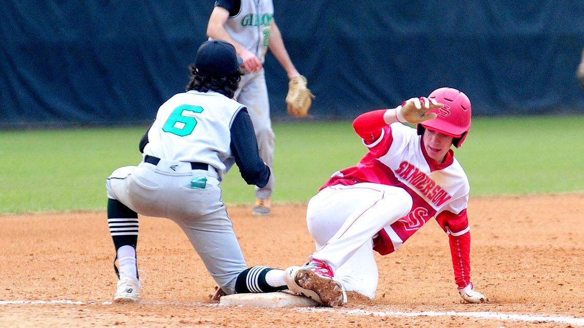 Sanderson High School’s Caleb Kleven (right) slides into third base ahead of the tag by Cardinal Gibbons High’s Drew Sotell (6) in this 2018 file photo.