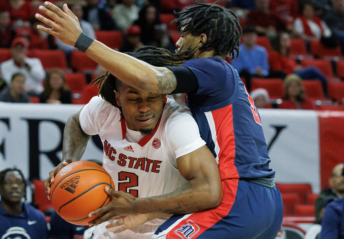 N.C. State’s Kam Woods drives against Detroit’s Kyle LeGreair during the first half of the Wolfpack’s game on Saturday, Dec. 23, 2023, at PNC Arena in Raleigh, N.C.