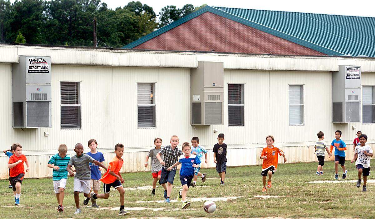 Second graders at Highcroft Drive Elementary School in Cary, N.C., play together on a grassy field next to a modular unit behind the school in this 2015 file photo.