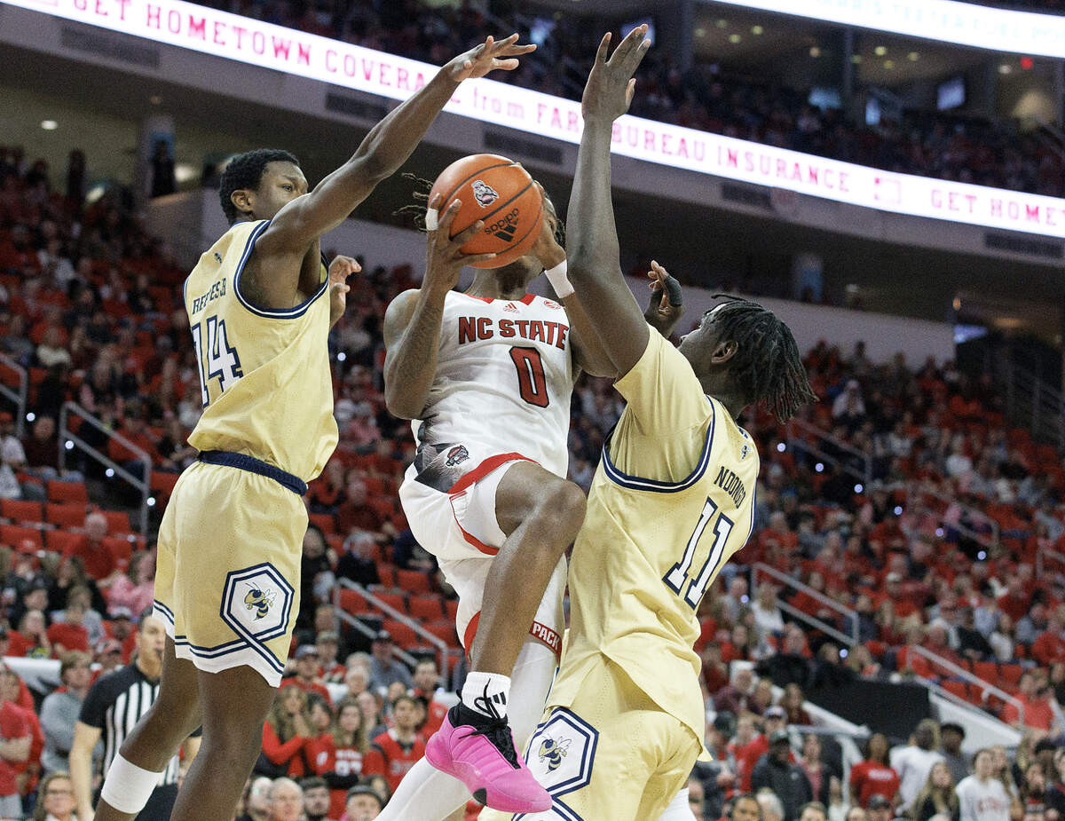 N.C. State’s DJ Horne drives past Georgia Tech’s Kowacie Reeves Jr. and Baye Ndongo during the second half of the Wolfpack’s 82-76 win on Saturday, Feb. 3, 2024, at PNC Arena in Raleigh, N.C.