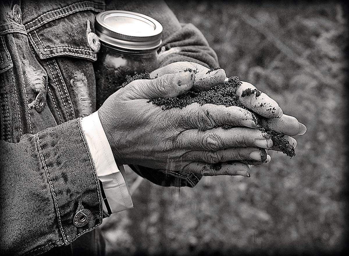 A participant gathers soil from the ground between her hands during a 2019 ceremony memorializing Manley McCauley, an 18-year-old Black man who was killed in 1898 near Carrboro for eloping with a married white woman.