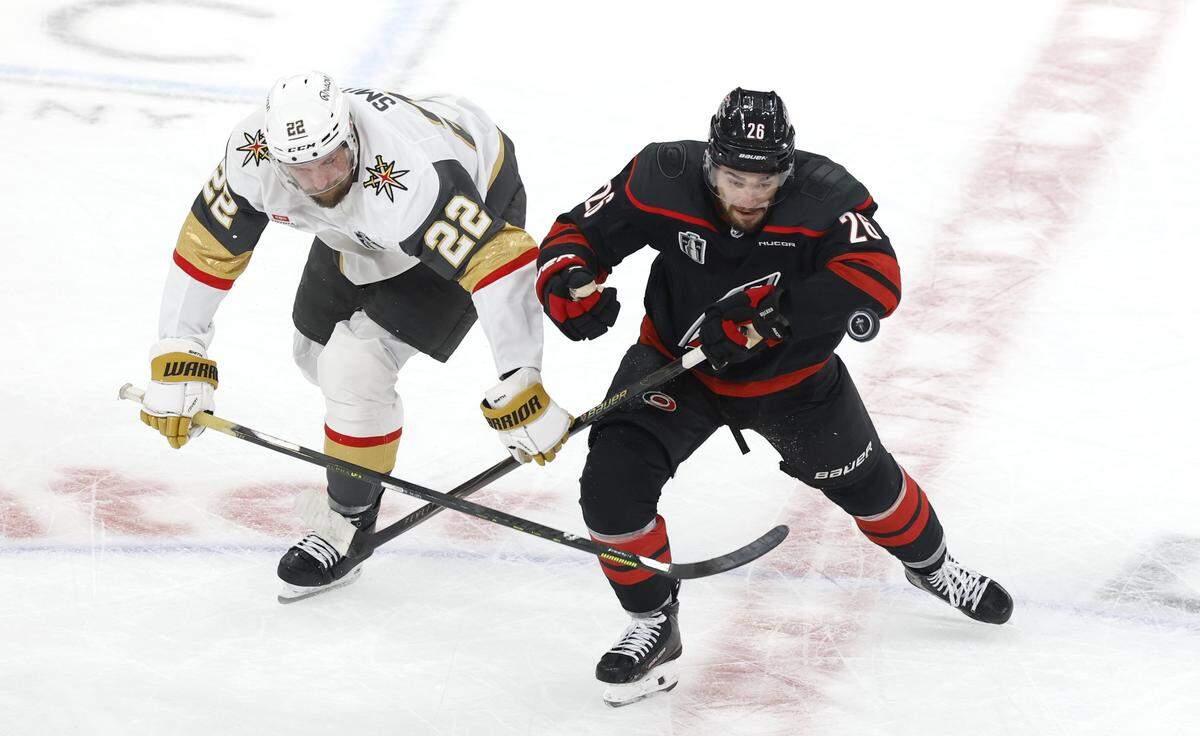 Carolina's Sean Walker (26) and Vegas’ Cole Smith (22) go after the puck in the first period of the Hurricanes’ game against the Golden Knights in the first game of the Stanley Cup Final at the Lenovo Center in Raleigh, N.C., Tuesday, June 2, 2026.