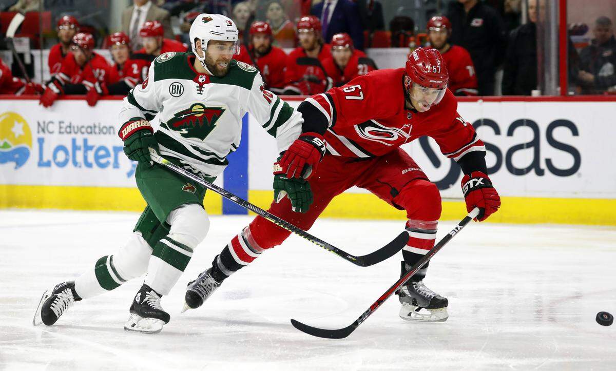 Minnesota Wild’s Jason Zucker (16) chips the puck ahead of Carolina Hurricanes’ Trevor van Riemsdyk (57) during the first period of an NHL hockey game, Saturday, March 23, 2019, in Raleigh, N.C. (AP Photo/Karl B DeBlaker)