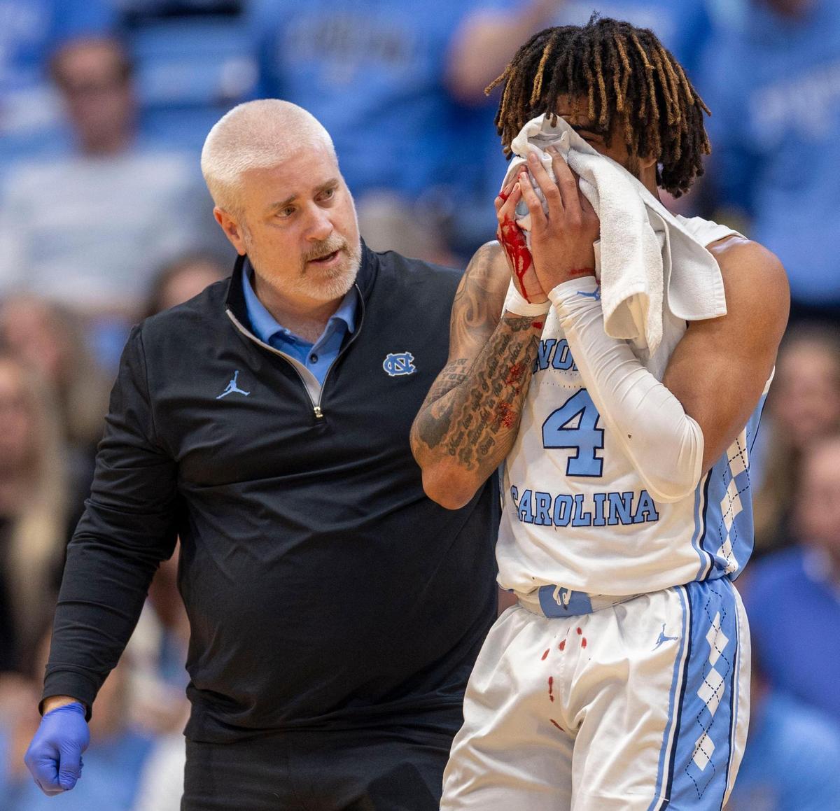 North Carolina trainer Doug Halverson escorts North Carolina guard R.J. Davis (4) off the court with a bloody nose, after scoring 26 points and lead the Tar Heels to an 82-67 victory.