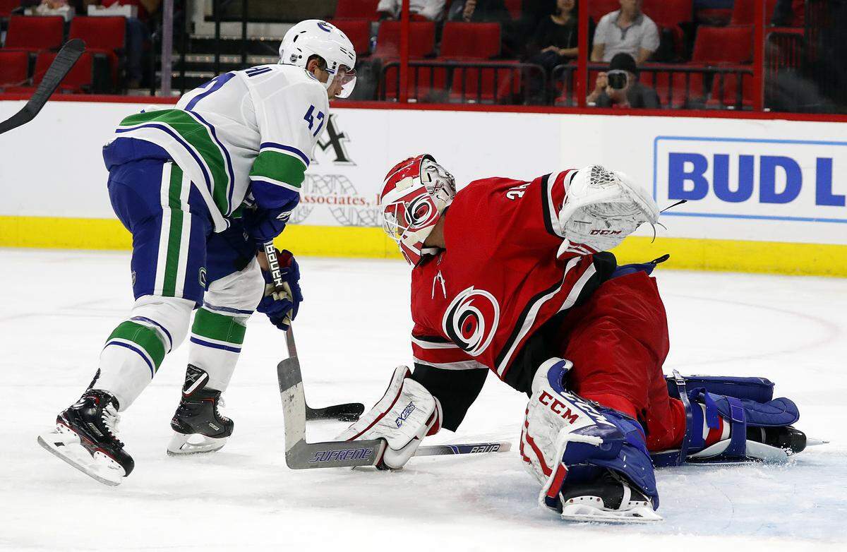 Carolina Hurricanes goaltender Curtis McElhinney (35) tries to block the shot of Vancouver Canucks’ Sven Baertschi (47) during the first period of an NHL hockey game, Tuesday, Oct. 9, 2018, in Raleigh, N.C.