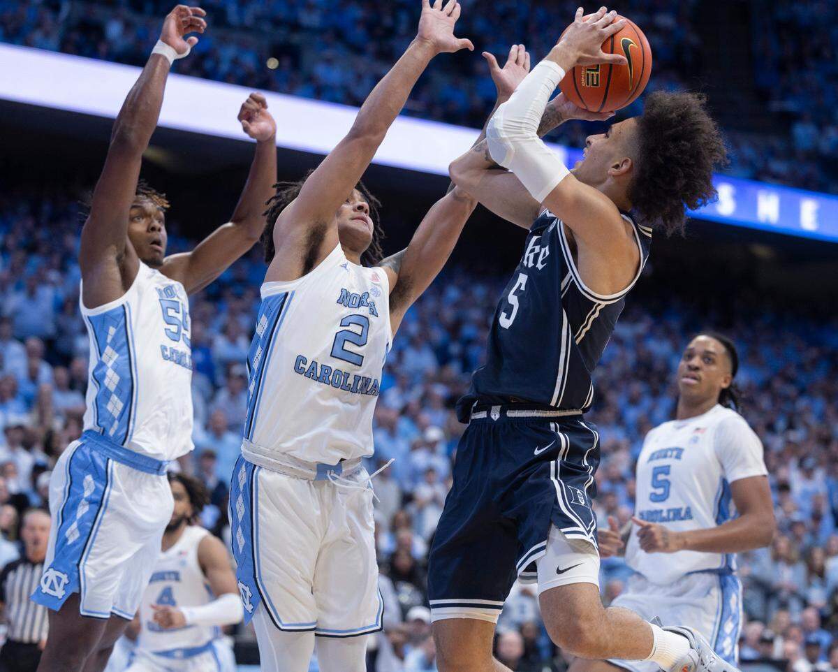 North Carolina’s Harrison Ingram (55) and Elliot Cadeau (2) defend Duke’s Tyrese Proctor (5) in the first half on Saturday, February, 3, 2024 at the Dean E. Smith Center in Chapel Hill, N.C.
