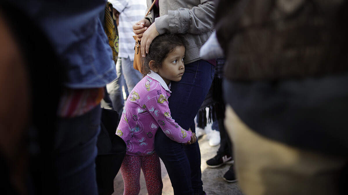 Nicole Hernandez holds onto her mother as they wait with other families to request political asylum in the United States on June 13, 2018 The Mexican family said it hopes to escape widespread violence. (Gregory Bull/AP Photo)