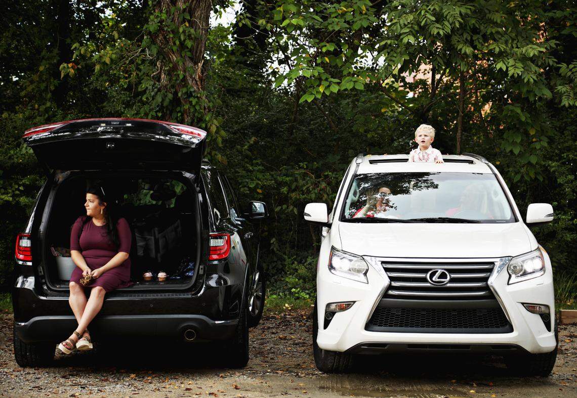Guest Lindsey Carusone, left, and Vance Taylor, right, watch from their cars as Carrie and John Michael Simpson exchange vows at their wedding ceremony on Sunday, Sept. 27, 2020, in Youngsville. The couple decided to have their ceremony in the parking lot of the Victorian House so that they could invite more guests who could watch from their cars. They also live-streamed the wedding for others who couldn’t attend in person.