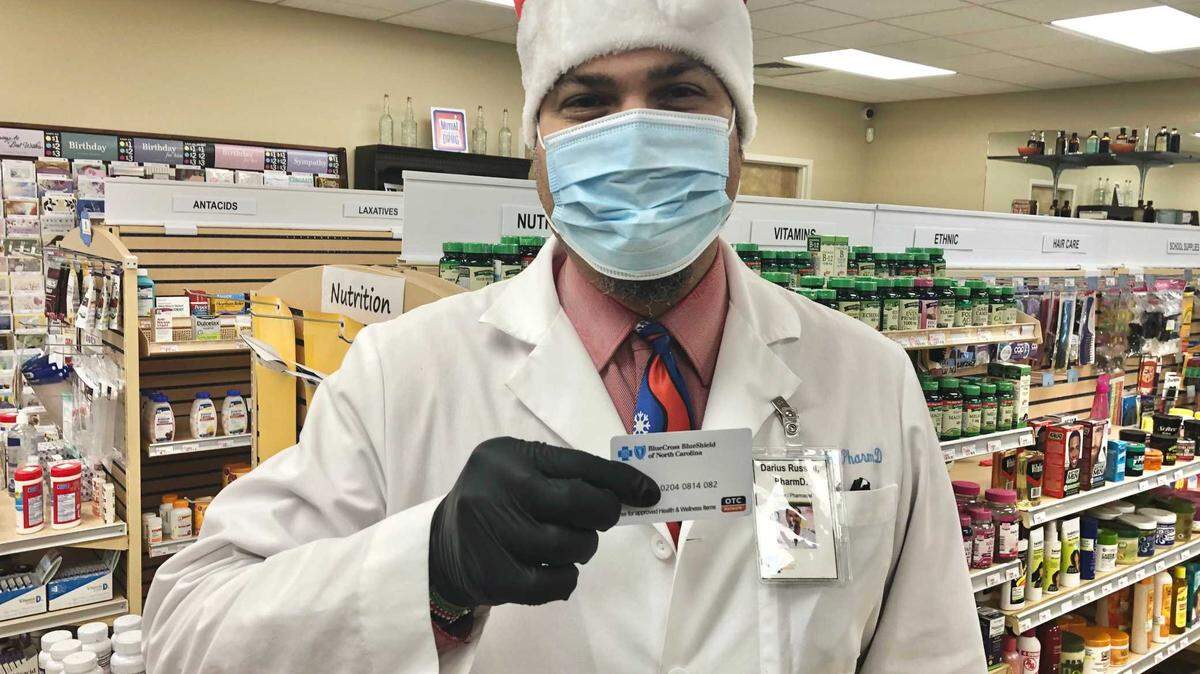 Darius Russell, pharmacist at Russell’s Pharmacy & Shoppe in Durham, holds a Blue Cross NC retail card in his pharmacy on Tuesday, Dec. 8, 2020.