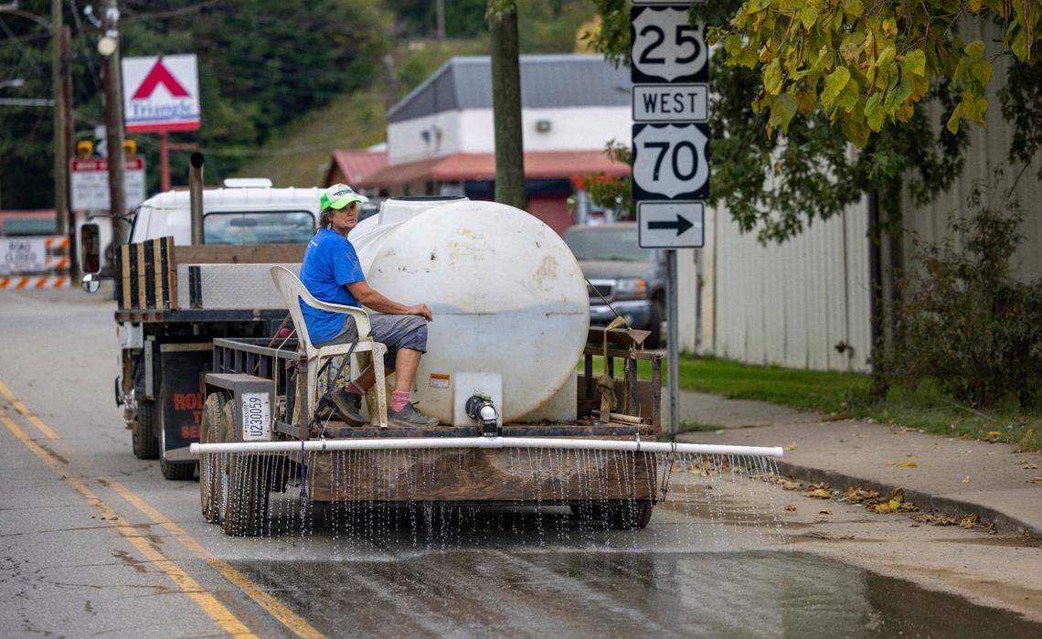 Jenifer Miller of Hot Springs, N.C. uses water, gravity and ingenuity to solve a growing dust problem, as mud from historic flooding turns to dust on Friday, October 4, 2024 in downtown Hot Springs, N.C.