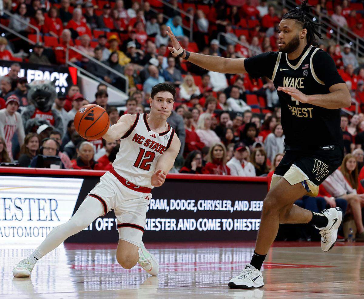 N.C. State’s Michael O’Connell passes around Wake Forest’s Efton Reid III to find Ben Middlebrooks for a dunk during the second half of the Wolfpack’s 85-73 win on Saturday, Feb. 22, 2025, at Lenovo Center in Raleigh, N.C.
