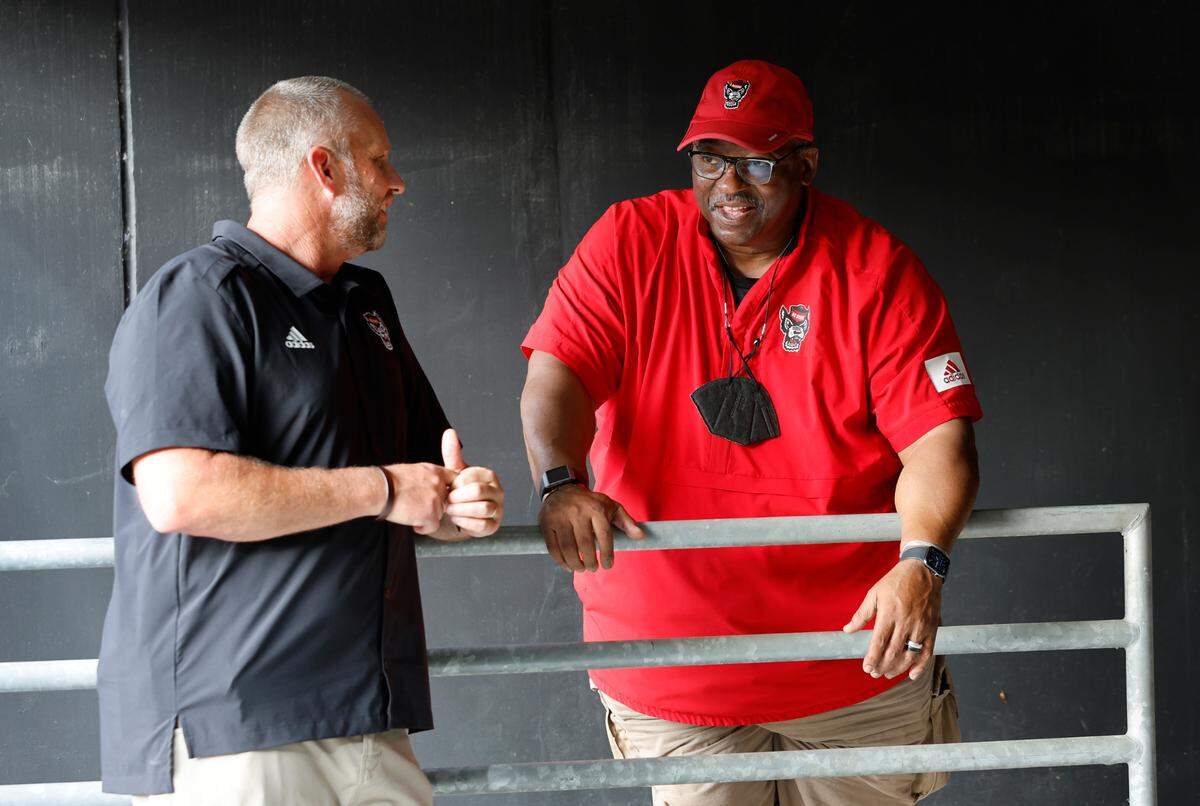 N.C. State head coach Dave Doeren, left, talks with Ruffin McNeill, special assistant to the head coach, during the Wolfpack’s Victory Day at Carter-Finley Stadium in Raleigh, N.C., Friday, August 5, 2022. On Victory Day, the Wolfpack partner with GiGi’s Playhouse, giving cognitively and physically impaired children a chance to play football alongside the Pack.