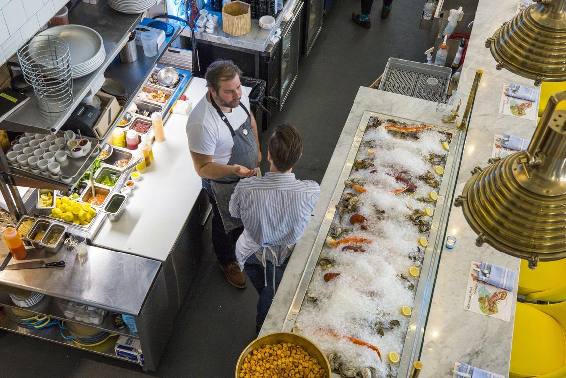 Chef Matt Kelly talks with Sous Chef Glenn Osterberg as guests begin to trickle in for dinner at Saint James Seafood in Durham.